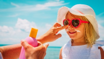 adult putting sunscreen on child's face)