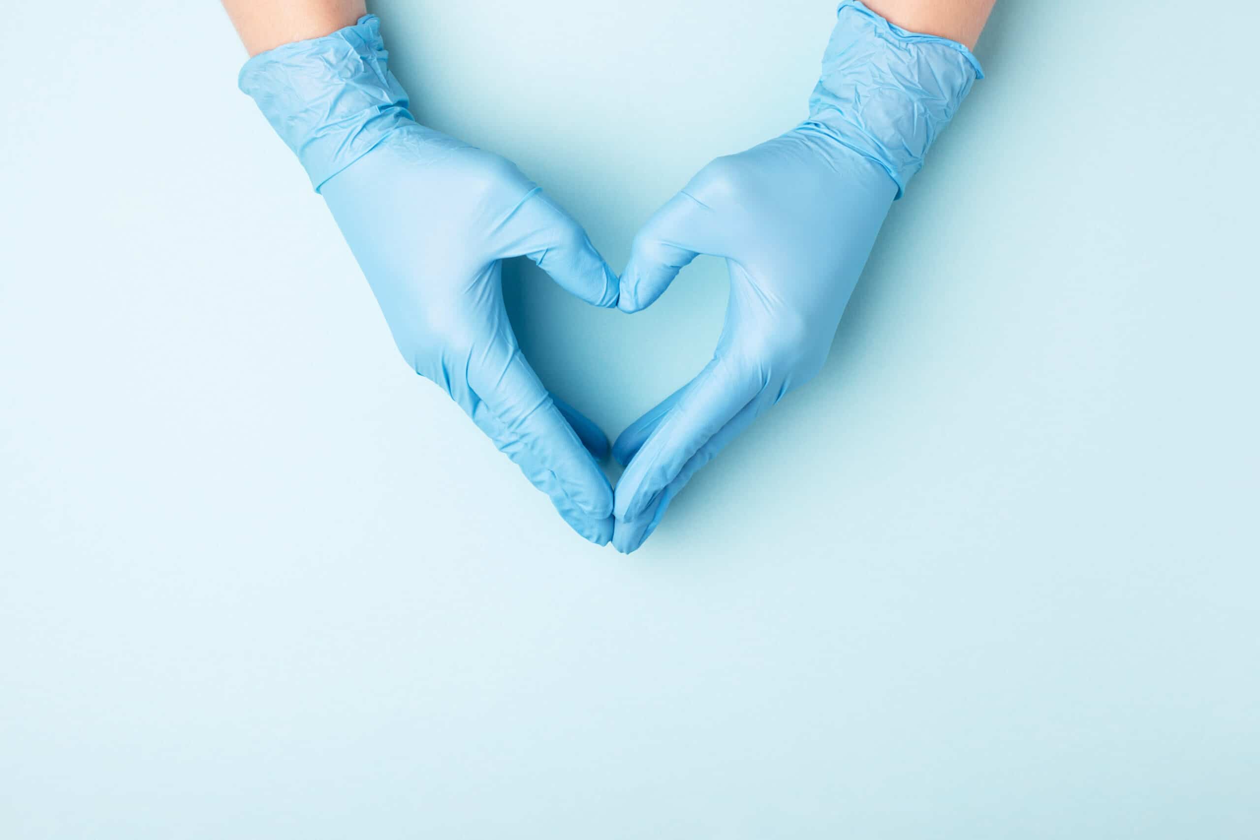 Dermatologist's hands in medical gloves in shape of heart